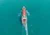 Aerial view of a cargo ship navigating through turquoise waters