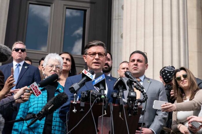 A group of individuals at a press conference with a speaker at a podium