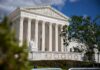 The Supreme Court building with columns and a statue in front