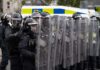 Riot police in formation with shields preparing for crowd control