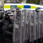 Riot police in formation with shields preparing for crowd control