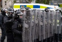 Riot police in formation with shields preparing for crowd control