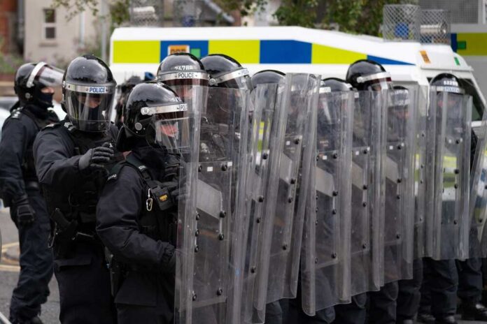 Riot police in formation with shields preparing for crowd control
