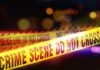 Yellow police tape marking a crime scene with blurred lights in the background