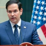 Marco Rubio speaking at a podium with an American flag in the background