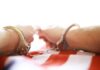 Hands in handcuffs resting on a striped surface
