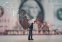 A miniature figure observing stock market graphs and financial data