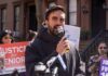 Man speaking into a microphone at a public rally for senior justice