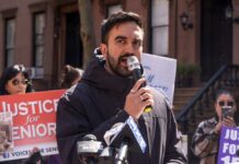 Man speaking into a microphone at a public rally for senior justice