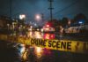 Police cars at a crime scene with caution tape in the foreground