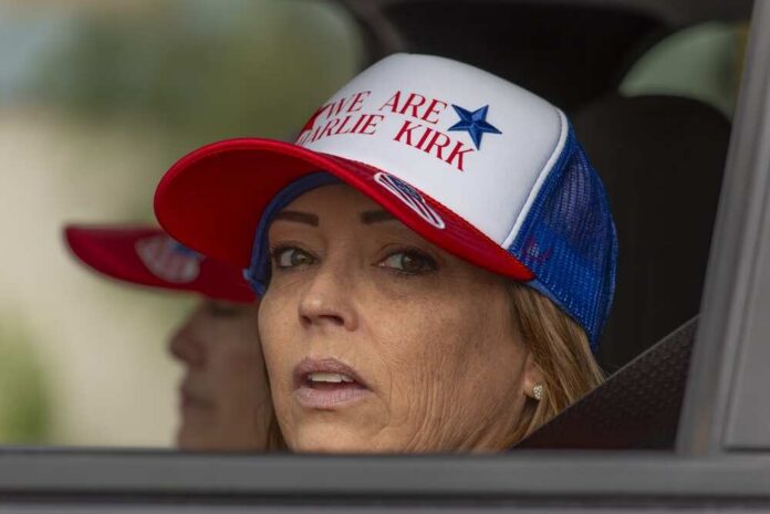 shutterstock_2743176407.jpg A woman wearing a cap with a political message, looking out from a vehicle