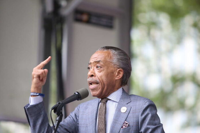 A speaker passionately addressing an audience with a raised hand