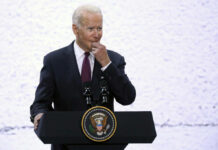 A man in a suit speaking at a podium with a presidential seal