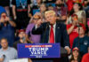 Donald Trump speaking at a political rally with a crowd in the background
