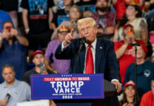 Donald Trump speaking at a political rally with a crowd in the background