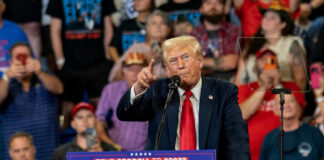 Donald Trump speaking at a political rally with a crowd in the background