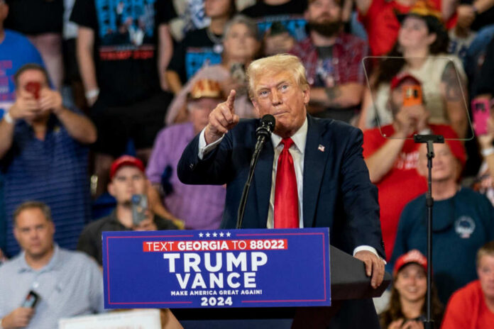 Donald Trump speaking at a political rally with a crowd in the background