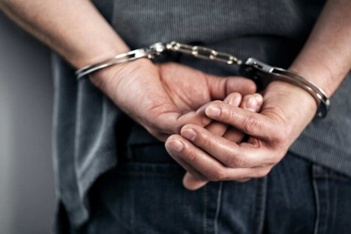 Hands cuffed behind the back, indicating arrest