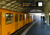 Yellow subway train at a station with commuters waiting