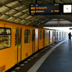 Yellow subway train at a station with commuters waiting
