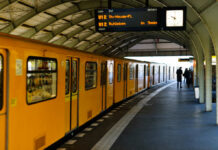 Yellow subway train at a station with commuters waiting