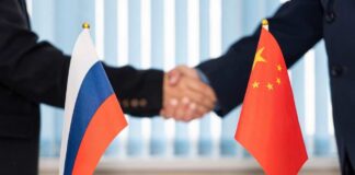 Handshake between two individuals with Russian and Chinese flags in the foreground