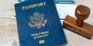 A U.S. passport, boarding pass, and a wooden stamp on a wooden surface