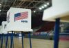 Voting booths with American flags set up in a gymnasium