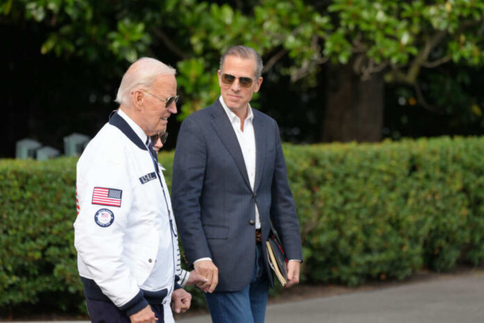 Two men walking outdoors, one in a jacket with an American flag, the other in a blazer