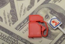 Red fuel pump toy next to hundred dollar bills