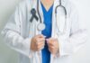 Healthcare professional wearing a white coat and stethoscope, with a black ribbon on their chest