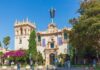 Historic building in Balboa Park with vibrant flowers and visitors