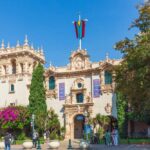 Historic building in Balboa Park with vibrant flowers and visitors