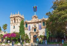 Historic building in Balboa Park with vibrant flowers and visitors