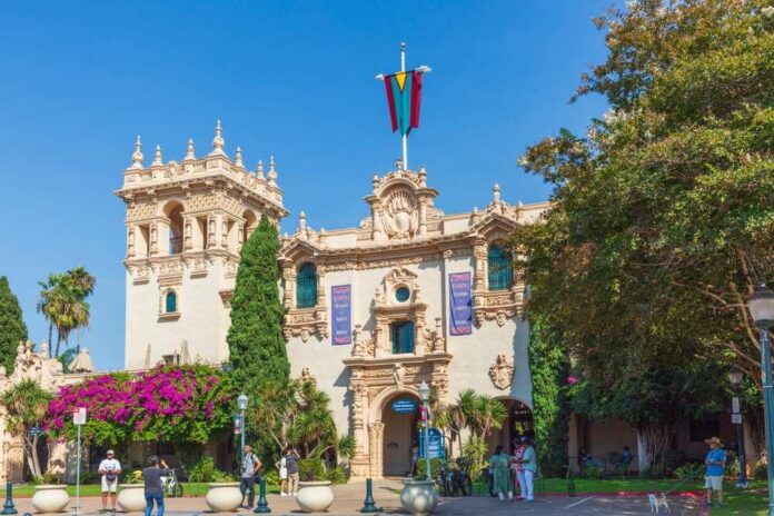 shutterstock_2569297003.jpg Historic building in Balboa Park with vibrant flowers and visitors