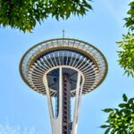 View of the Seattle Space Needle surrounded by green leaves against a blue sky