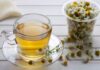 A cup of chamomile tea next to a container of chamomile flowers