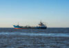 A cargo ship sailing on the ocean under a clear blue sky