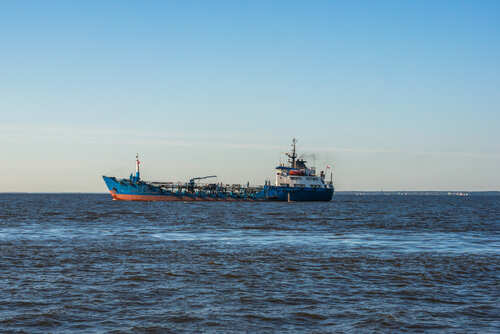 A cargo ship sailing on the ocean under a clear blue sky