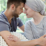 A couple sharing a tender moment, foreheads touching, in a cozy setting