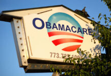 Sign displaying Obamacare with a blue and red logo against a clear sky