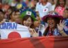 Japanese soccer fans cheering with flags in a stadium