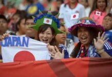 Japanese soccer fans cheering with flags in a stadium
