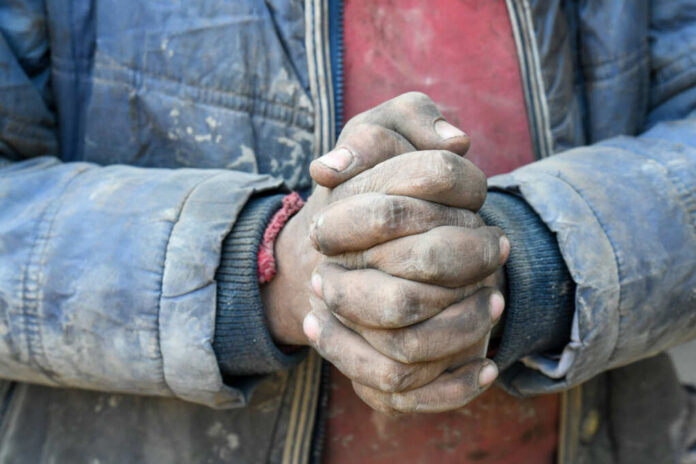 shutterstock2079928024jpg Close-up of dirty hands clasped together, wearing a blue jacket