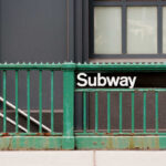 Subway entrance with a green railing and a sign reading Subway