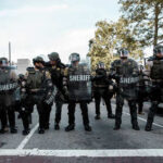 Law enforcement officers in riot gear standing in formation