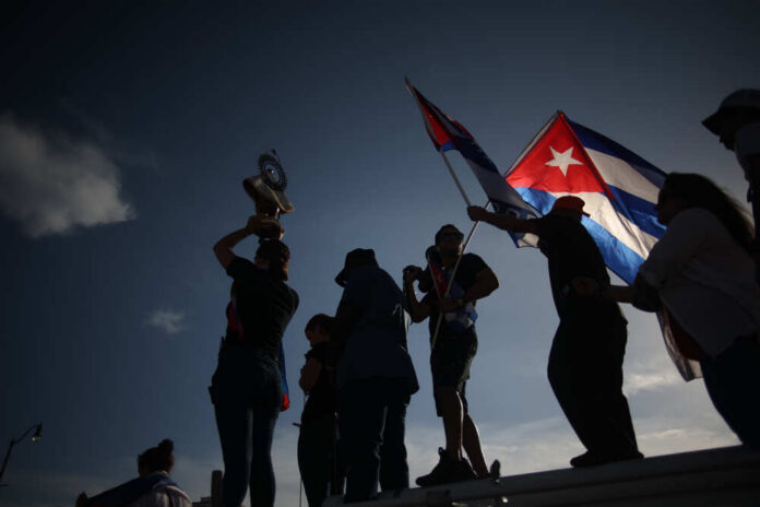 Miami,,Fl,,United,States,-,July,11,,2021:,Cuban,Exiles Silhouetted figures celebrating with a trophy and Cuban flags against a sunset sky
