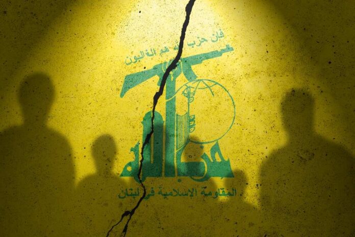 Silhouettes of two figures against a yellow background featuring Hezbollah's emblem