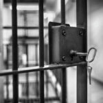 Close-up of a jail cell lock with a key hanging