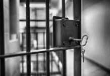 Close-up of a jail cell lock with a key hanging